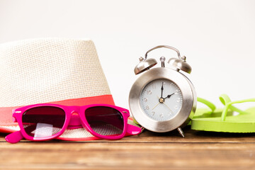 Closeup shot of sunglasses and a hat near an alarm clock - vacation time concept