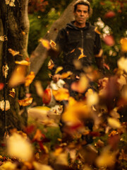 Un homme passe le soufflant dans son jardin , en premier plan on voit les feuilles d'automne qui s'envolent.