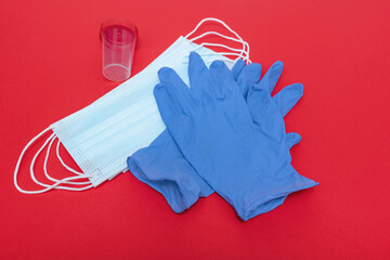 Medical mask to protect against corona virus. On a red background. Blue gloves. Analysis container.