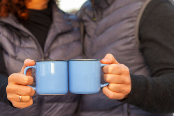 blue cups in the hands of a couple in love close-up, selective focus