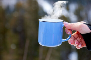 blue enameled mug in a female hand in winter