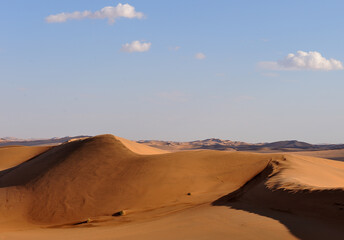 Fototapeta na wymiar The sun beating red on Namib desert dunes, edged against a blue sky