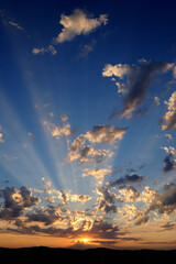 Spectacular sunset in the Namib Desert with a fiery sun and broken clouds