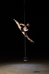 Obraz na płótnie Canvas Beautiful young pole dancer woman on pylon isolated on black background.