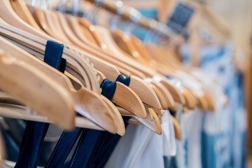 Fototapeta premium Ladies Clothes on wooden hangers in shelf fashion for sale in shopfront store, retail background.