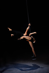 Man and woman doing exercises on pylon isolated on black background.Pole dance concept.