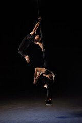 Man and woman doing exercises on pylon isolated on black background.Pole dance concept.