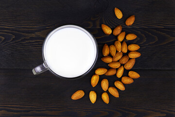 Glass of Almond milk and almond nuts on dark wooden background. Healthy nut vegan drinks concept. Top view. Flat lay.