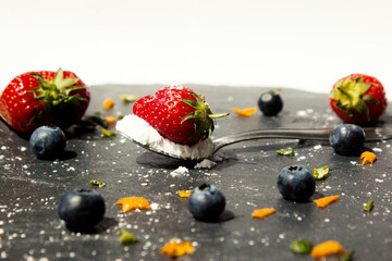 a strawberry with powdered sugar on a teaspoon