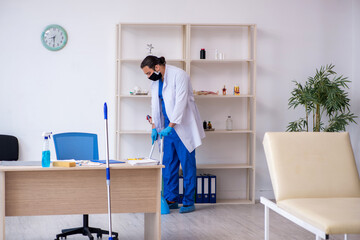 Young male contractor disinfecting clinic in pandemic concept