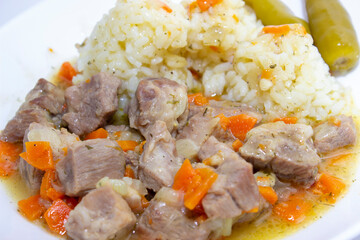 Hot dish of pilaf with meat and rice. White plate, white background top view