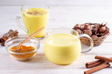 Healthy ayurvedic drink golden almond milk with curcuma powder on white background, close-up. Trendy Asian natural detox beverage with spices for vegans