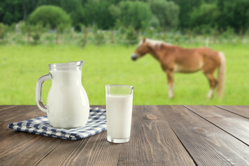 Fresh koumiss milk on wooden tabletop and blurred landscape.