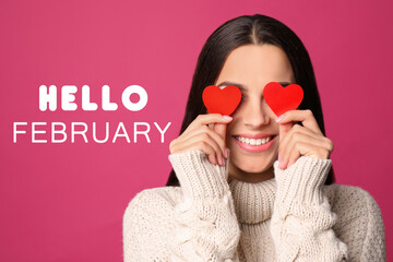 Greeting card with text Hello February. Young woman holding paper hearts near eyes on pink...