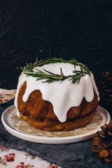 xmas cake with dried fruits decorated with fir tree branch, over black background