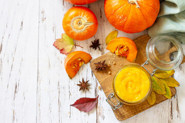 Pumpkin Puree with spices and Pumpkin on a wooden table. Top view flat lay background. Copy space.