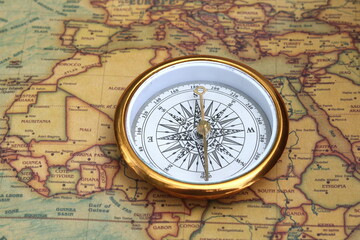 Classic round compass on background of old vintage map of world as symbol of tourism with compass, travel with compass and outdoor activities with compass