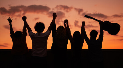 Fototapeta premium Anonymous friends with raised arms on rooftop in evening