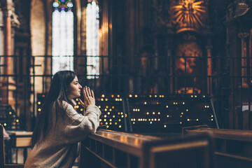 a young pretty woman came to the temple to pray to God. The parishioner of the church sits on a...