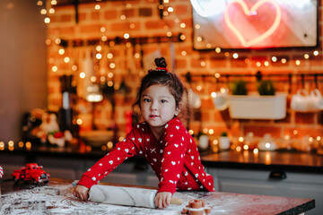  little asian girl roll out the dough for Christmas cookies on the kitchen