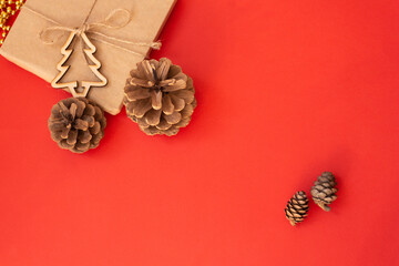 Christmas red background, craft gift pine cones gold beads snowflakes. Christmas red background