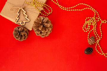 Christmas red background, craft gift pine cones gold beads snowflakes. Christmas red background