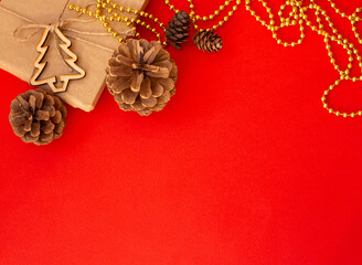 Christmas red background, craft gift pine cones gold beads snowflakes. Christmas red background