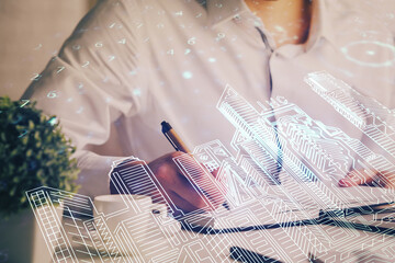 Abstract holographic city on man's hand writing notes background. Multi exposure.