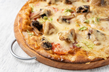 Vegetarian pizza with mushrooms on wholegrain flour dough on a light table close-up