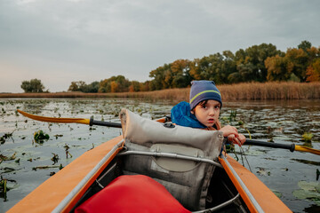 Evening kayak trip along the river in autumn. The active lifestyle of the child in the family.
