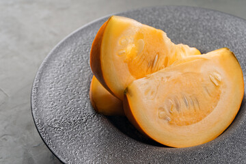 Pumpkin slices on a gray concrete plate close-up