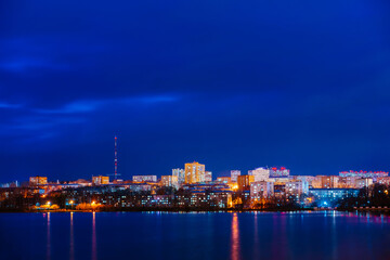 Obraz premium A night panorama of city with illuminated buildings. Izhevsk pond. 