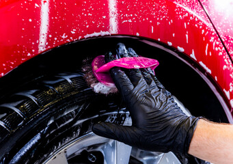 Cleaning the car wheel with a brush and water