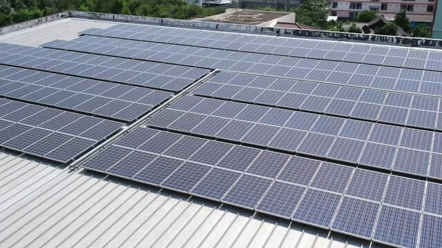 Many solar panels are on the roof of a large facility.