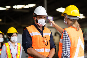 Temperature measurement with employee temperature meter before entering work at factory. Professional engineering team.