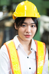 Woman worker wearing safety goggles at Metal lathe industrial manufacturing factory. portrait of cheerful young Asian woman wearing hardhat smiling happily looking at camera