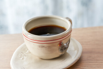 Close-up of a cup of coffee for afternoon tea in the sunlight by the window