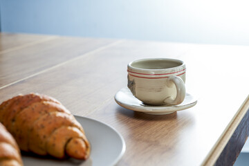 A plate of French croissant and coffee for afternoon tea in the sun by the window