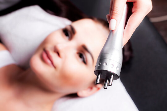 Tripolar RF-lifting apparatus in the foreground, in the background the woman patient is out of focus.