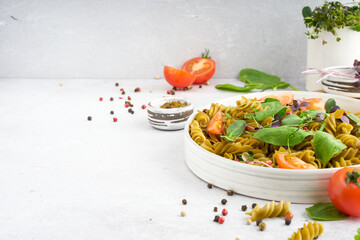 Green spinach pasta with microgreen and pesto in a white bowl with silver cutlery. Gourmet italian meal. Top view. Flatlay. Copy spase. Concept health eating