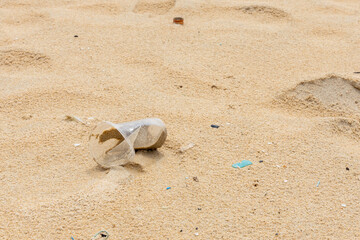 A plastic glass and other litter garbage was left on the beach. Environmental care and recycle concept.