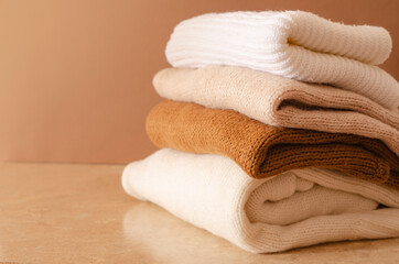 Autumn winter clothes concept. Pile of knitted beige clothes, warm background, knitwear.