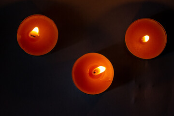 Composition of three candles on dark luxury night background. Black table, top view. Candles...