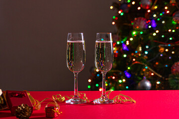 New Year's photo glasses on a red table with champagne on the background of the Christmas tree with lights and sides. Holiday and bull year