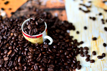 Coffee grains are poured into a small cup and spread around the table.