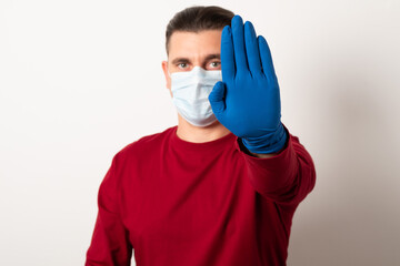 Man wearing a surgical mask and gloves during a pandemic. Studio image of a young man wearing a medical mask and gloves.