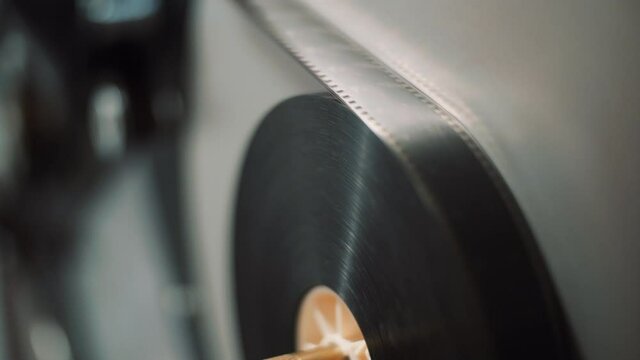 Roll with film tape loaded on a projection machine. The tape rotates.