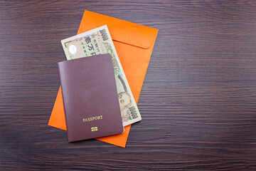 International passport and japanese banknotes on orange envelope at table brown dark wood. Top view