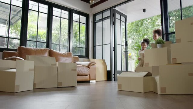 Candid african american family, parents and little girl holding carton box walk into new house move in day,relocate in existing second hand home. Loan mortgage finance in real estate property concept.