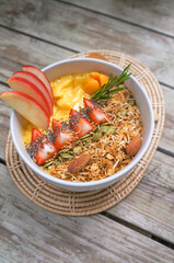 Healthy breakfast smoothie bowl: mango smoothie with banana, papaya, pineapple, almonds, sunflower and chia seeds and apple
